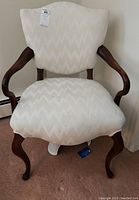 Front view of upholstered armchair showing cream fabric with chevron pattern and wooden curved arms and legs.