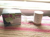 Photo shows two essential oil diffusers: an Onugi diffuser in its box and a standing DoTerra Cloud diffuser with visible power cord on a striped fabric surface.