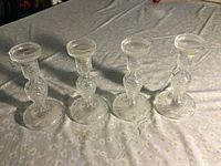 Side view of four Waterford crystal candlesticks on table, showing detailed etched pattern and full set of four.