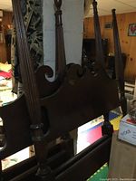 Close-up photo of the headboard showing the scroll design and turned posts with decorative finials on top.