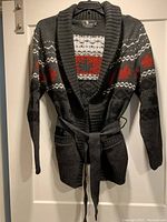 Full view of charcoal grey cardigan with red and white maple leaf pattern, ribbed collar and belt waist.