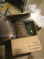 Open box showing multiple stacked citronella incense coils packaged flat and wrapped inside. The box is filled with many coils organized inside.