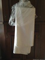 Folded Irish linen tablecloth covered in plastic, showing size and fabric type.