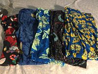Five pairs of Lula Roe leggings folded side by side showing colorful patterns including Christmas and floral designs.