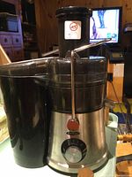 Front view of Omega juicer with stainless steel base, black plastic sieve, and chute with locking lever.