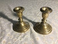 Photo of pair of sterling silver weighted candlesticks on floral cloth.