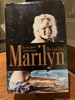 Photo of "Marilyn The Last Take" hardcover book showing dust jacket with image of Marilyn Monroe and water imagery, plus title and author text.