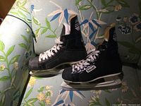 Photo of a pair of vintage Bauer men's hockey skates in size 9.5 D on a floral background, showing right side profile and left skate in back.