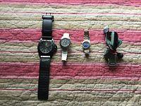 Front view of all four watches laid out horizontally showing different strap materials and dial styles.
