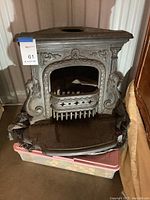 Full front view of the antique cast iron stove showing ornate designs and top rounded opening.