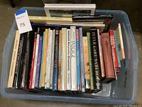 Top view of plastic bin full of craft, sewing, and art books stacked upright and sideways