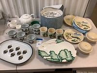 Full view of the various china items arranged on a table showing platters, cups, bowls, and plates.