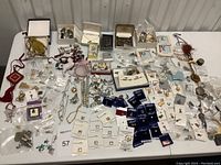 Wide shot of entire lot showing varied charm packs, necklaces, bracelets, and loose charms arranged on table.