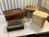Five vintage style boxes and radio arranged on a table including an RCA radio, wooden boxes, and jewelry boxes.