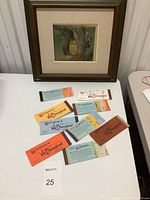 Overview of framed cel propped behind Disneyland ticket booklets on table