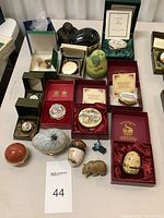 Overview of all enamel boxes, carved stone figures and enamel brooch on table
