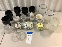 Wide view of all items including black goblets, frosted mugs, sugar bowls, salt shaker, thimble mug, yellow sugar bowl, and clear glassware.