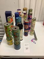 Overview of 15 vintage kaleidoscopes with various colorful designs arranged on a white table.