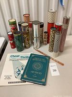 Whole collection of 14 vintage kaleidoscopes shown upright with two books/magazine on the table in front