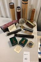 Group view of multiple wooden and metal kaleidoscopes with stands and decorative glass globe on table