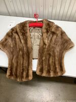 Brown mink fur shawl spread open on table showing the fur texture and front shape.