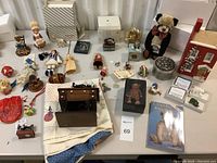 Full view of the collection of vintage decor including teddy bear themed items, sewing themed trinkets, ornaments, dolls, and books on a table.