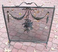 Full front view of antique brass ormolu fireplace screen placed outdoors on brick pavers