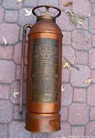 Top front view showing the copper body, metal guard ring on top, and the copper nozzle pipe.