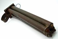 Side angle photo showing the four conical tubes of the antique tin candle mold and loop handle for holding.