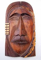 Front view of carved wooden mask showing detailed facial features and wood grain.