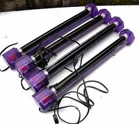 Four purple-ended tubular fluorescent light bars with black cords, displayed side by side