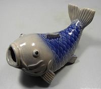 Side view of ceramic koi carp fish brush holder showing the grey head and blue scales on the body.