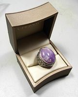 Amethyst cabochon cocktail ring displayed in a beige gift box with the lid open, showing the ring cushioned inside.