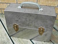 Front view of the lunch box showing the dual brass latches and handle on top.
