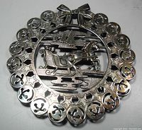 Top-down view of the silverplate Christmas trivet showing the detailed sleigh and horse design in the center with anchor and star border and bow accent.