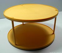 Photo showing side view of the gold colored two-tier lazy susan with solid top and bottom shelves connected by four supports.