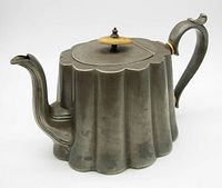 Front left angle view of antique Wheatley Brothers Sheffield teapot showing fluted body, curved spout, hinged lid with wooden finial.