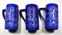 Three blue ceramic vintage mugs with Portmeirion Totem pattern, showing embossed geometric designs and angular handles, on white background.