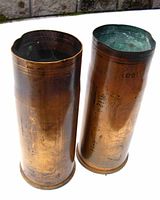 Two brass military shell casings standing upright showing surface wear and dented rims.