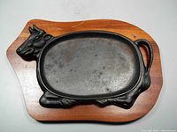 Top view of cast iron serving tray shaped like a cow mounted on wooden base