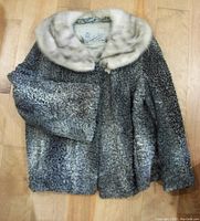 Full front view of the vintage Persian lamb fur coat with creamy mink collar, laid flat on wooden floor.