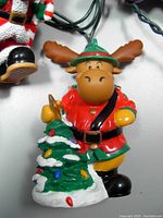 Close-up of moose figurine in red RCMP uniform holding decorated Christmas tree, soft vinyl light cover on string light