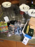 Three large clear canisters with white lids and assorted small packaged items around