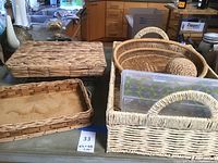Overview of six decorative baskets including woven wicker and rattan styles and a plastic storage container on kitchen counter