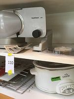 Shelf showing electric food slicer and Crock-Pot together