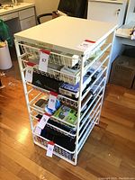 Front perspective of white Elfa wire basket organizer with 6 drawers and white wood top.