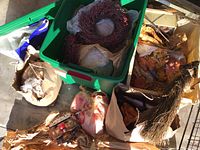 Overall view of green plastic storage bin with red twig wreath and multiple boxes and bags containing autumn decorations including artificial leaves, pine cones, and garlands.