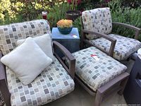 Two lounge chairs and accompanying ottoman arranged outdoors
