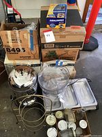 Wide shot showing stainless steel beverage dispenser, clear plastic dispenser, mason jars, food warmer trays, and cardboard boxes