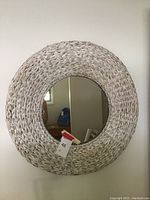 Front view of round wicker mirror showing the woven wicker frame and reflective glass surface.